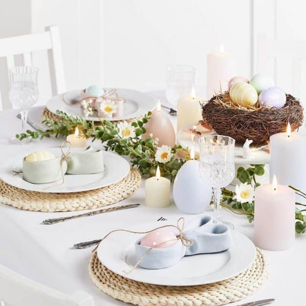 Svátečně prostřený stůl pro velikonoční sváteční oběd s vejíčky v hnízdě a svíčkami