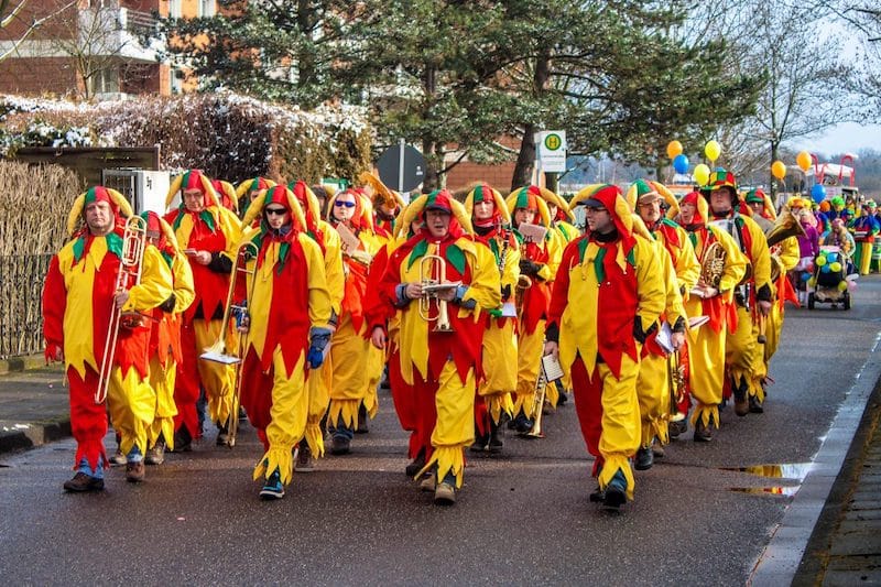 Průvod na německý fašank, kdy jsou muzikanti oděni do pestrobarevných, žlutočervených šatů a kráčejí ulicí.